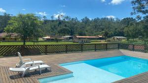 a swimming pool with a bench and a chair next to it at Chácara sabor de Mel in Ibiúna
