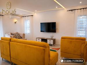 a living room with two yellow couches and a tv at Résidence Houé 