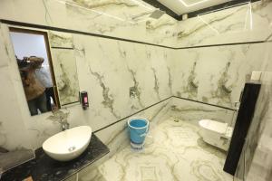 a man taking a picture of a marble bathroom with a sink at Hotel Prabhawati Palace Near Railway Station and Sri Vishwanath Temple Varanasi in Varanasi