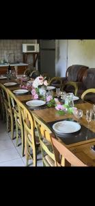 a long wooden table with plates and flowers on it at Gîte proche de La Salvetat in Le Soulié
