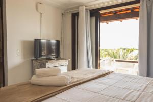 a bedroom with a bed with a tv and a window at Arambare Buzios Hotel in Búzios +114 photos