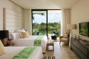 a hotel room with two beds and a large window at Rosewood Mayakoba in Playa del Carmen