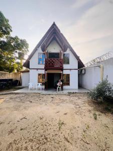 a house with two white chairs in front of it at Cabaña Niva in Coveñas