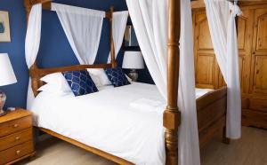 a bedroom with a four poster bed and blue walls at Le Gîte des Violettes in Ger