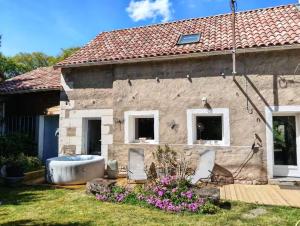 a stone house with a tub in the yard at La fermette de Chandigon in Antran +15 photos