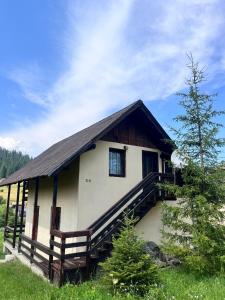 a small house with a wooden porch and a tree at Vacation home E in Borsec