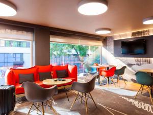 a lobby with a red couch and tables and chairs at Hotel ibis Lisboa Liberdade in Lisbon