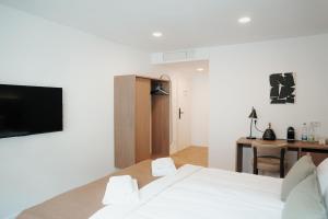 a bedroom with a bed and a desk with a television at The Haus KAI Nuremberg in Nuremberg