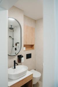 a bathroom with a sink and a toilet and a mirror at The Haus KAI Nuremberg in Nuremberg +49 photos