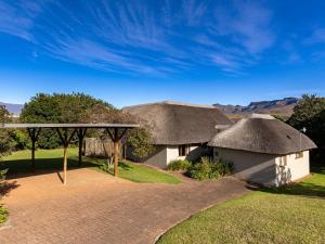 a house with a thatched roof and a driveway at Montusi Self-Catering Cottages in Bergville