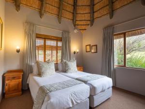 a bedroom with two beds and two windows at Montusi Self-Catering Cottages in Bergville +101 photos