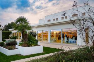 a white building with palm trees in front of it at Villa Natia in Mottola