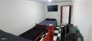 a room with a bed and a table and a television at Hostel Canarios in Palhoça