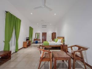 a room with green curtains and a bed and tables at Grandpa's villa Jaffna in Jaffna