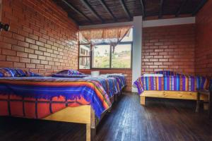 two beds in a room with a brick wall at PatulomaEscape in El Rosario