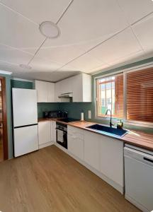 a kitchen with white cabinets and a white refrigerator at El refugio de NaRo in Chella