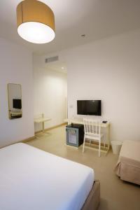 a bedroom with a bed and a tv and a chair at Villa Natia in Mottola