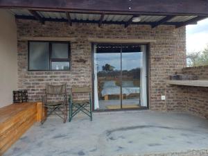 a patio with two chairs and a brick wall at BosSpoke Bush Lodge in Thabazimbi