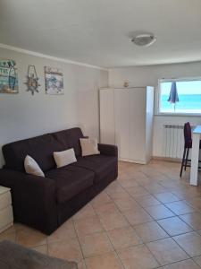 a living room with a black couch and a window at CASINA SULLa SABBIA in Torvaianica