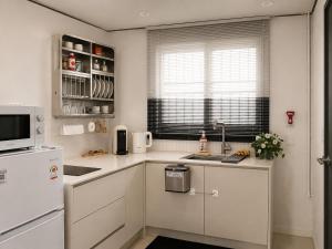 a kitchen with white cabinets and a white refrigerator at Yoonsul Gwangalli 3beds for 4guests in Suyŏng