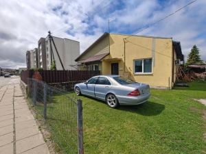 a car parked in the grass in front of a house at Cozy Spark Studio Apartment in Kelmė