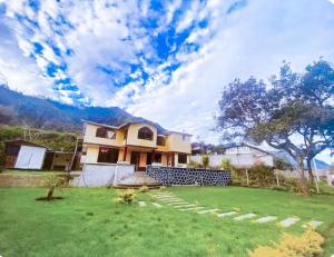 a house with a green yard in front of it at Casa Refugio del Amanecer en Baños de Agua Santa in Lligua