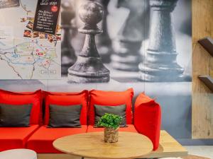 a red couch with red pillows and a table at Ibis Bilbao Barakaldo in Barakaldo