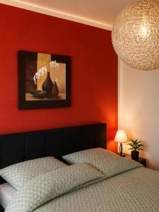 a bedroom with a red wall with a bed and a painting at Pension Zum Rödereck in Zeithain