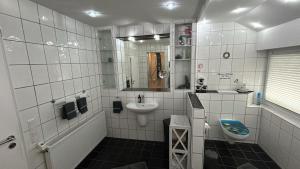 a white tiled bathroom with a sink and a toilet at Apartment Grieshop in Dinklage +8 photos
