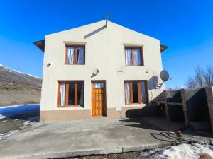 a small white house with a brown door at La Colina in Río Mayo