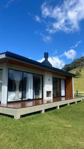 a house with a large deck with windows on it at Cabana No Lago in Rancho Queimado