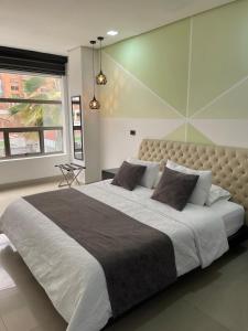 a bedroom with a large bed in a room with a window at Hotel Merlott 70 in Medellín