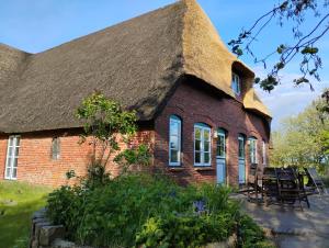 an old brick house with a thatched roof at Ferienwohnungen Am Westerdeich in Rodenäs