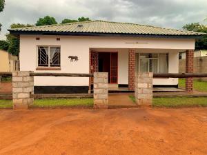 a small house with a cow on the side of it at Larry's Lodge in Livingstone