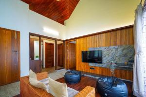 a living room with a tv on a wall at Open Hotel by Olive - Biranji Aqua Reatreat in Chikmagalūr