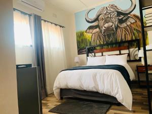 a bedroom with a painting of a bull on the wall at Larry's Lodge in Livingstone