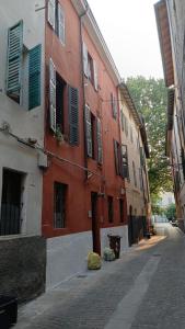 a red building with green shutters on a street at B&B Casa Merulo- Camera singola con bagno privato in Parma