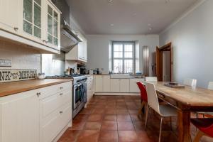 a kitchen with a wooden table and white cabinets at Corner House - Elie & Earlsferry in Elie