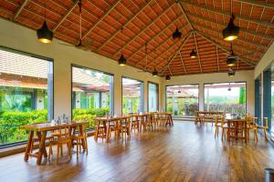 a restaurant with wooden tables and chairs and windows at Open Hotel by Olive - Biranji Aqua Reatreat in Chikmagalūr