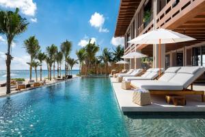 an infinity pool with lounge chairs and umbrellas at a resort at Rosewood Mayakoba in Playa del Carmen