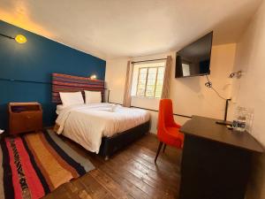 a bedroom with a bed and a desk and a television at Anido House in Ollantaytambo