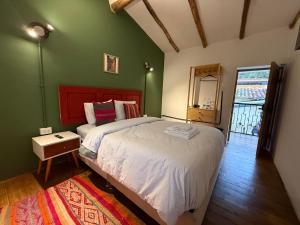 a bedroom with a bed and a green wall at Anido House in Ollantaytambo