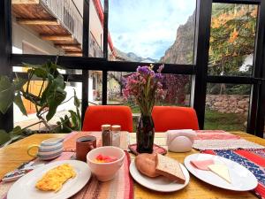 a table with plates of food and a vase of flowers at Anido House in Ollantaytambo