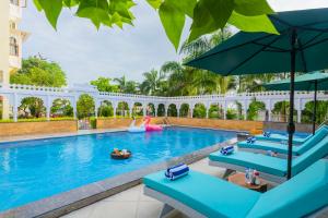 a pool at the resort with blue chairs and an umbrella at Manas Resort Udaipur in Udaipur