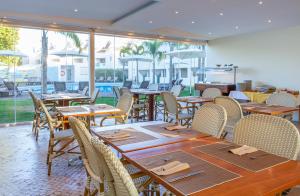 a restaurant with wooden tables and chairs and windows at Lagoa Hotel in Lagoa