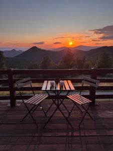 a table and two chairs with the sunset in the background at Brvnara Jevtic, Tara in Mokra Gora