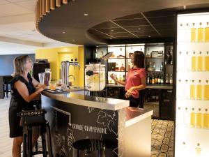 two women standing at a counter in a bar at Ibis Styles Cognac in Châteaubernard