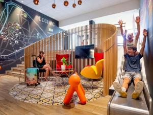 two people are playing on a slide in a room at Ibis Styles Cognac in Châteaubernard