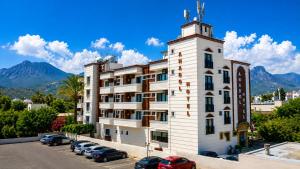 a large white building with cars parked in a parking lot at ANADOL Hotel & Pool Central Kyrenia in Temblos +19 photos