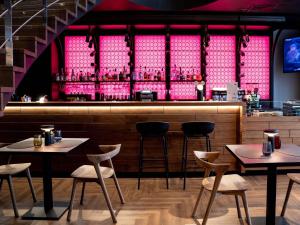 a restaurant with tables and a bar with pink lights at Novotel Vilnius Centre in Vilnius